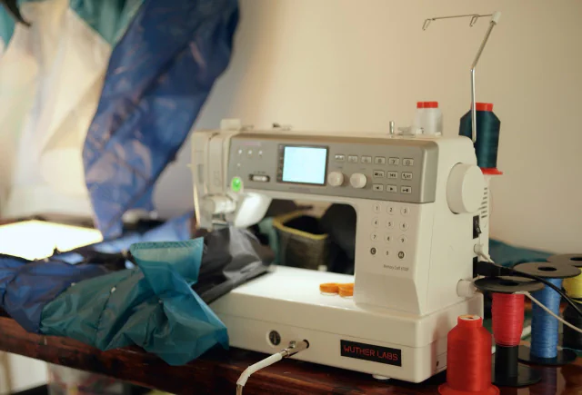 Machine à coudre avec une étiquette Wuther Labs, bobines de fil coloré et tissu de l’aile