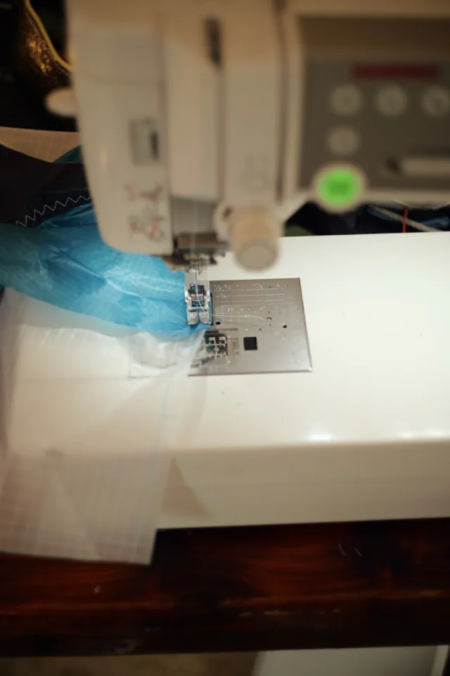 Tissu ripstop turquoise et blanc sous le pied presseur de la machine à coudre