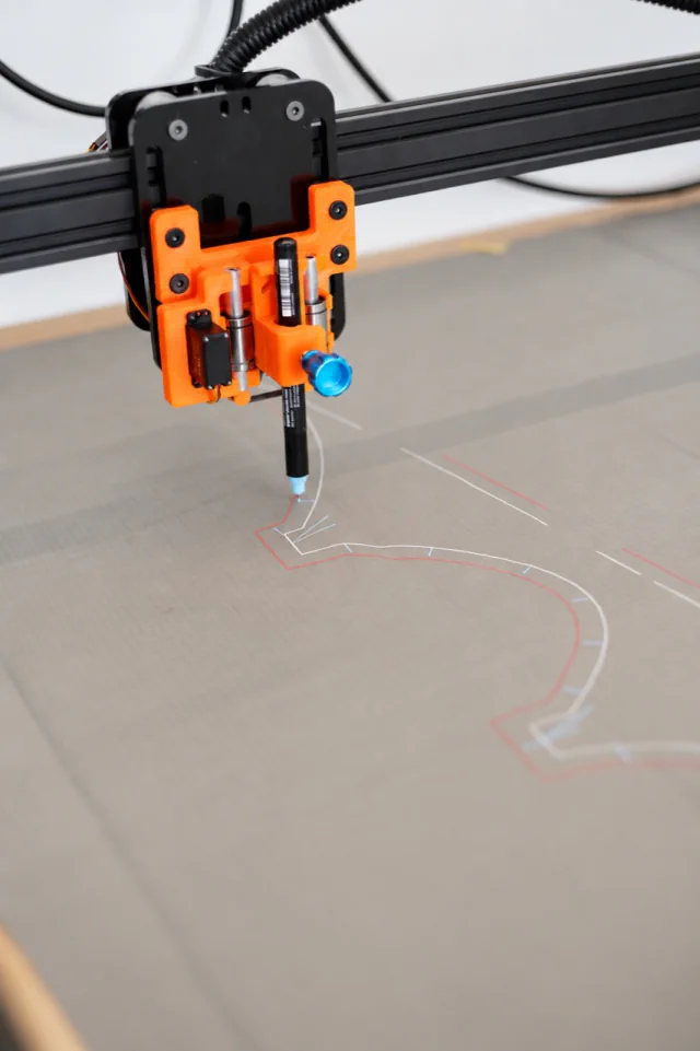 Traceur dessinant des repères de patron rouges et blancs sur le tissu ripstop translucide